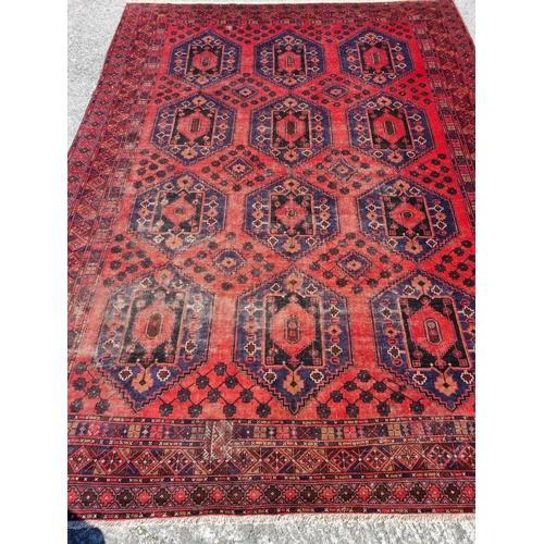 831 - A large vintage red ground Baluchi Carpet with an all over diamond design. 374 x 271 cm approx.
