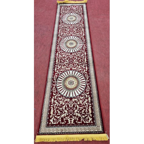 852 - A Cashmire silk style runner with red ground. 310 x 77 cms approx.