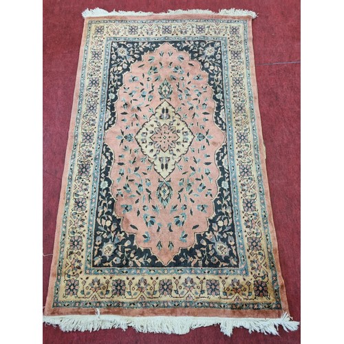 30 - A pink ground Rug with central motif. 210 x 125 cms approx.