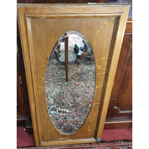31 - An early 20th Century Oak mirror with oval bevelled glass. 50 x 48 cm approx.