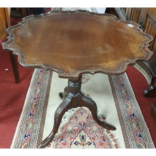 61 - An early 19th Century Mahogany Supper table with scalloped edge on carved tripod supports. Diam.75 x... 