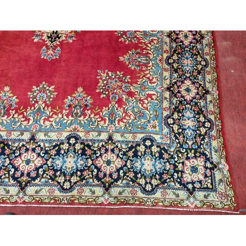 413 - A beautiful full pile red ground Persian Kerman Carpet with central medallion design and a floral bo... 