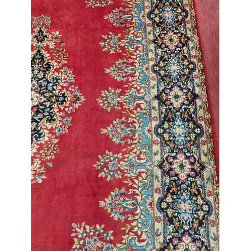 413 - A beautiful full pile red ground Persian Kerman Carpet with central medallion design and a floral bo... 