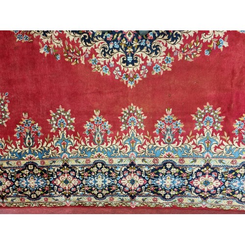 413 - A beautiful full pile red ground Persian Kerman Carpet with central medallion design and a floral bo... 