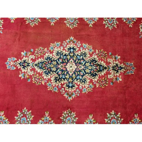 413 - A beautiful full pile red ground Persian Kerman Carpet with central medallion design and a floral bo... 