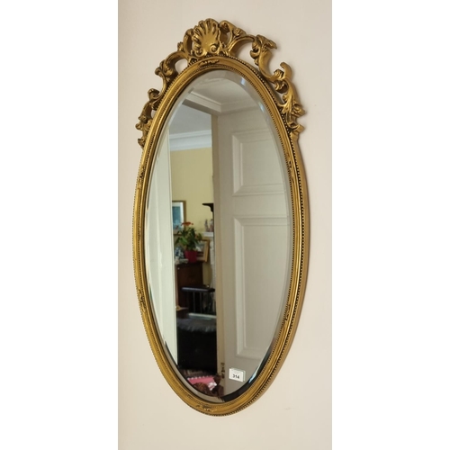 314 - A good bevelled oval Gilt Mirror with carved cartouche top.  41 x 78 cm approx.