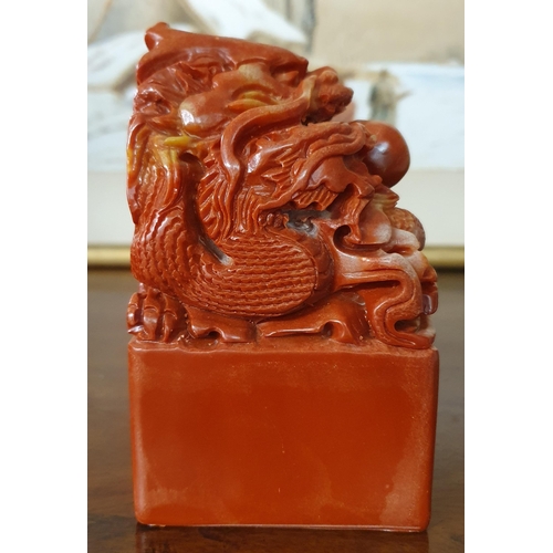 886 - A Chinese carved red hardstone desk Seal in the form of a squatting dragon on a square block base. 1... 