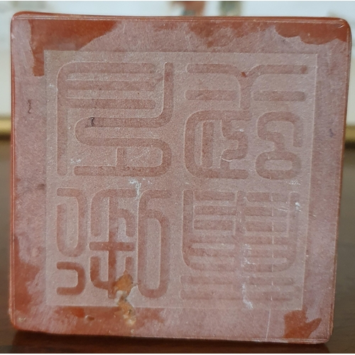 886 - A Chinese carved red hardstone desk Seal in the form of a squatting dragon on a square block base. 1... 