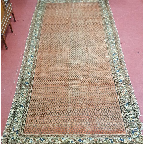 357 - A large red and cream ground Carpet with multi borders and repeating medallion design. Well worn wit... 