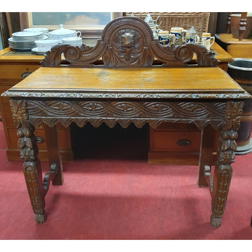 569 - A 19th Century Oak Hall Table with highly carved outline and single drawer side and mask head galler... 