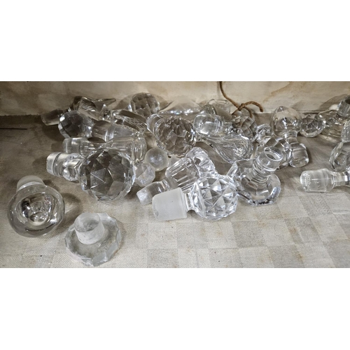 143 - A large collection of crystal Stoppers along with crystal knife Rests.