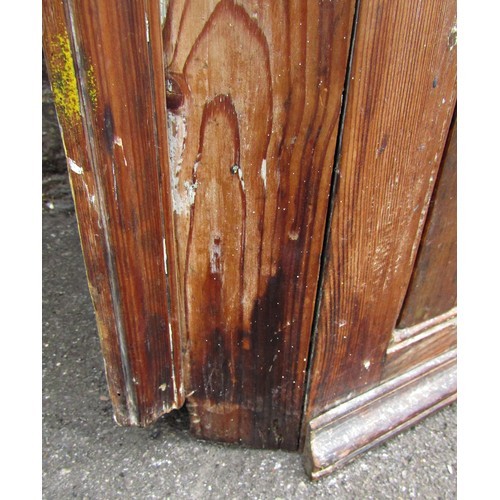 1054 - A 19th century stripped pine hanging corner cupboard enclosed by a single moulded panelled door with... 