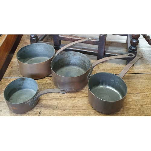 114 - A 19th Century graduated set of Copper Saucepans with cast iron handles.