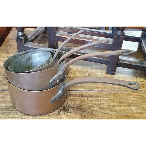 114 - A 19th Century graduated set of Copper Saucepans with cast iron handles.