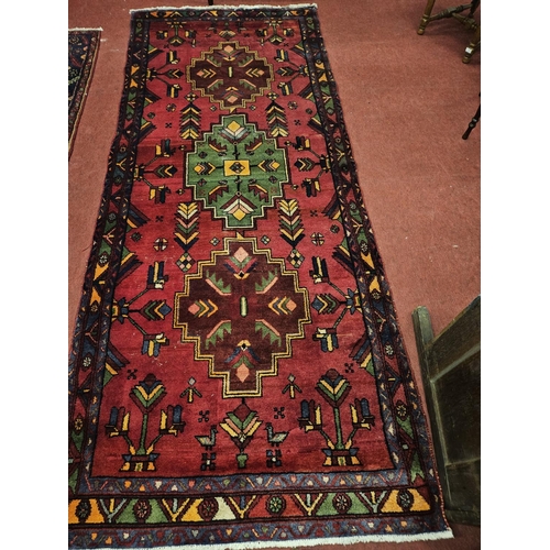 636 - A large Persian red and blue ground Rug/Runner with multi borders and repeating medallion design. 32... 