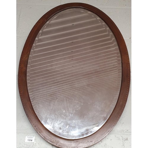 660 - An Edwardian and Mahogany inlaid oval Mirror. 74 x 49 cm approx.