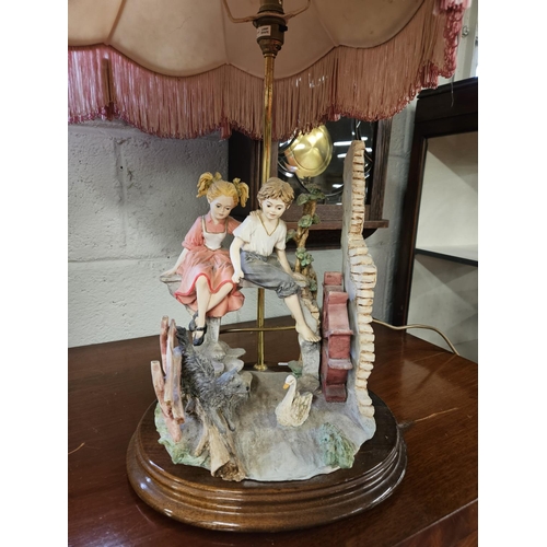 1134 - A good Table Lamp depicting two children playing beside a mill wheel. H 59 cm approx.