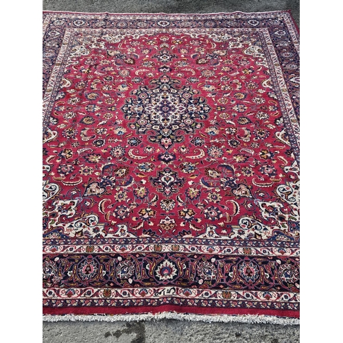 858 - A large Red ground hand woven Persian Mashhad Carpet with a central medallion design and a surroundi... 