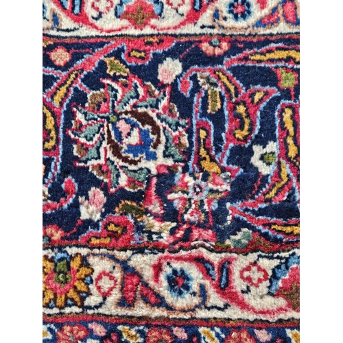 858 - A large Red ground hand woven Persian Mashhad Carpet with a central medallion design and a surroundi... 