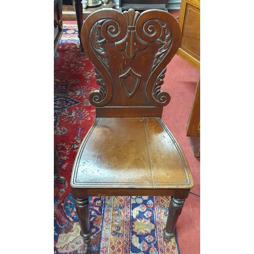 896 - A 19th Century Mahogany Hall Chair with highly carved back on turned supports.