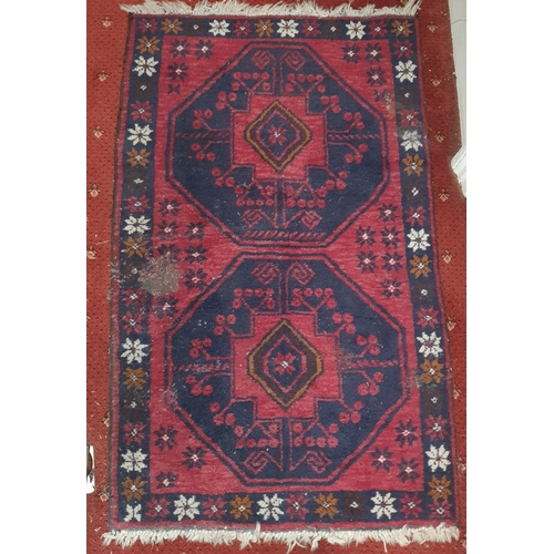 251 - A Persian red ground Carpet with repeating medallion central design. 84 x 140 cm approx.