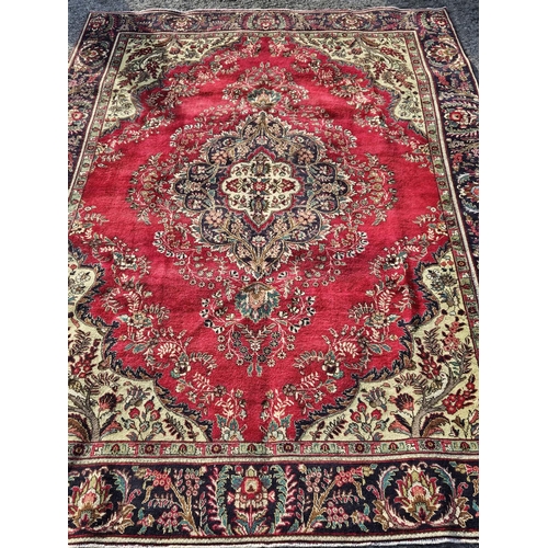 857 - A Red ground Persian Tabriz Carpet with a multi coloured field and a central pattern. 340 x 244 cm a... 