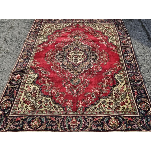 857 - A Red ground Persian Tabriz Carpet with a multi coloured field and a central pattern. 340 x 244 cm a... 