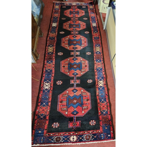 982 - A deep ground Persian Nahravan Runner with a repeating medallion design. 302 x 104cm approx.