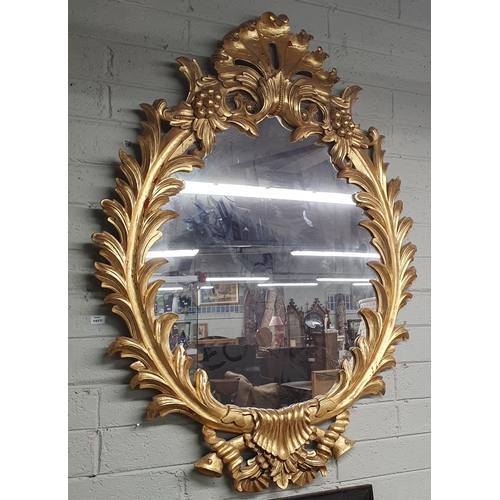 1077 - A very large Timber Gilt oval Mirror with highly carved cartouche top and frame. 138 x 104 cm approx... 