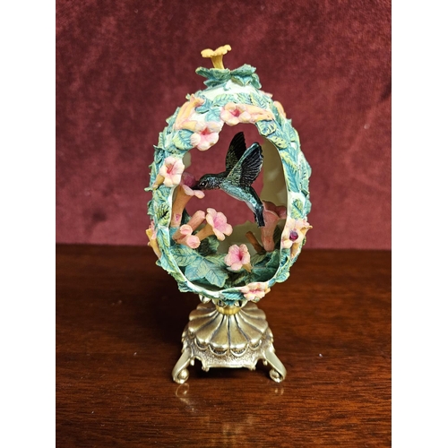 323 - From the house of Faberge, a moulded egg depicting a humming bird. H 12 cm approx.