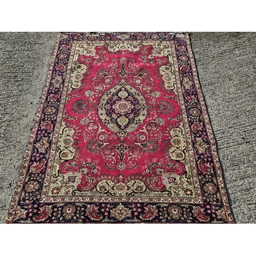 864 - A fine hand woven Persian Tabriz Carpet with a multi coloured central floral medallion design, 315 x... 