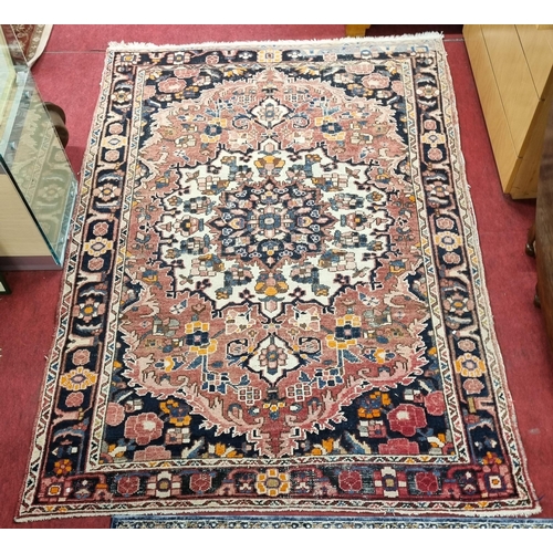 1083 - A good Terracotta ground hand woven Persian Carpet with a traditional medallion design from the Bakh... 