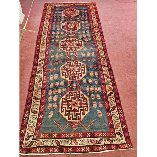 213 - A Persian Runner with red ground with multi borders and central aztec medallion design.  404 x 160 c... 