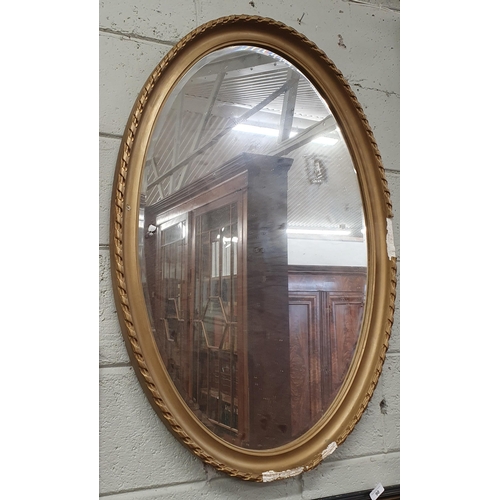 89 - A large late 19th early 20th Century oval Mirror. (in need of some restoration). 98 x 68 cm approx.