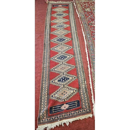 167 - A red ground Runner with a repeating central medallion design.  L 300 x W 75 cm approx.