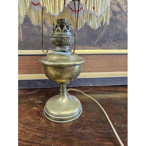 749 - An unusual early 20th Century converted Oil Lamp with tasseled outline. H 37 cm approx.