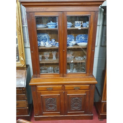 151 - A Victorian Walnut two door Bookcase with highly carved panelled doors with a glazed upper and twin ... 