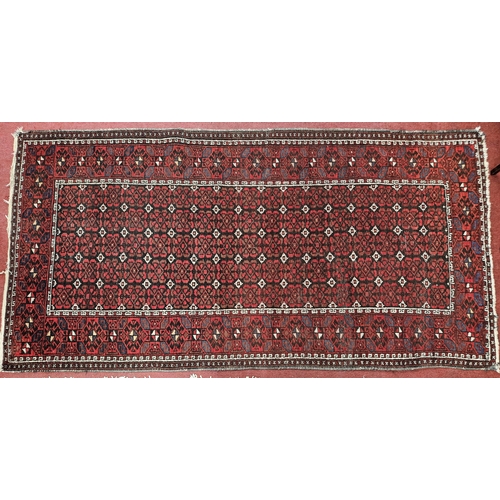 233 - A good Persian red ground Rug with repeating central medallion design and multi borders, 201 x 104 c... 