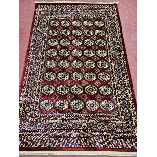 2 - A red ground Turkish Soft Full Pile Carpet with central repeated panel design surrounded by borders ... 