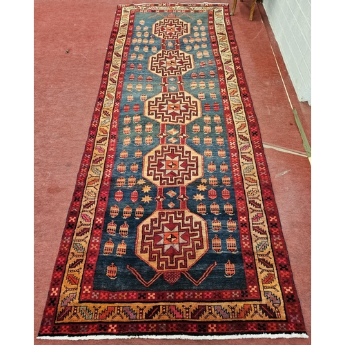 31 - A Persian Runner with red ground with multi borders and central aztec medallion design.  404 x 160 c... 