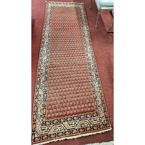 84 - A Persian red ground Runner with multi borders and repeating central medallion design.  322 x 107cm ... 