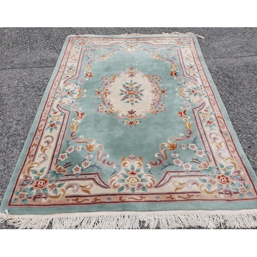 830 - An Oriental Green ground Carpet with floral design. 290 x 181 cm approx