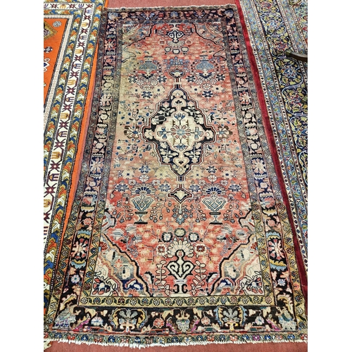 89 - A washed Persian Red ground Persian Sukh village Rug with a medallion design. 139 x 290 cm approx.