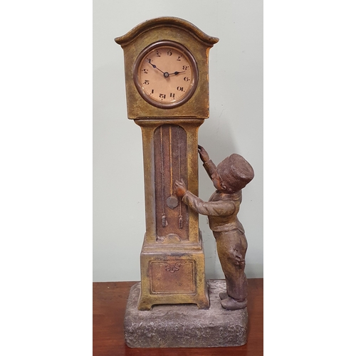 114 - A good Metal Clock depicting a boy winding a clock, on a plinth base.