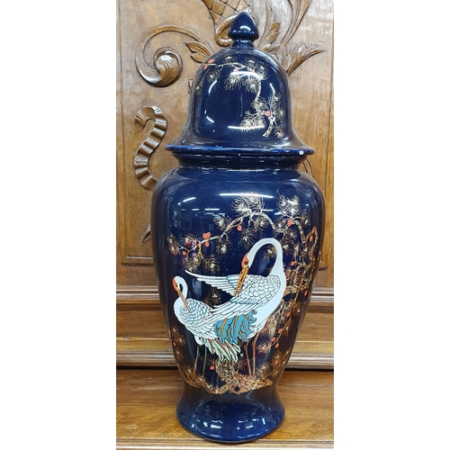 184 - A 20th Century hand painted blue ground Ginger Jar depicting birds of paradise. H 42 cm approx.