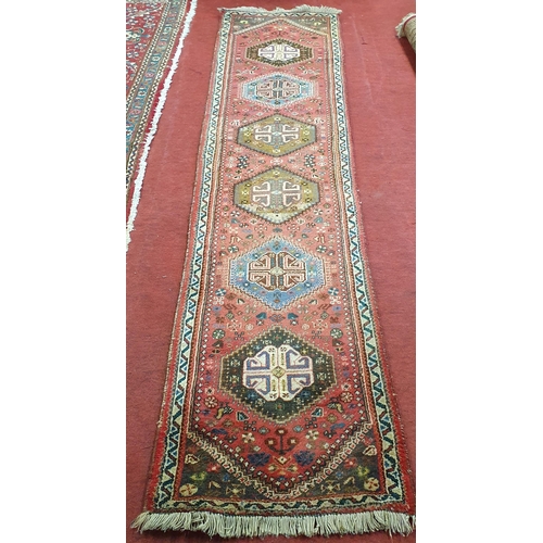 267 - A Persian red ground Runner with repeating central medallion design. 69 x 300 cm approx.