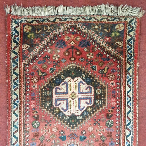 267 - A Persian red ground Runner with repeating central medallion design. 69 x 300 cm approx.