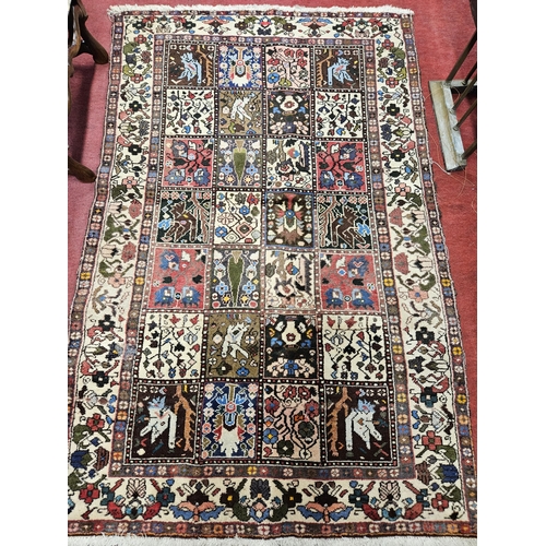 174 - A Persian cream ground Rug with central rectangular panel design and multi borders. Some slight faul... 