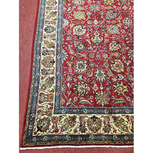 958 - A Red ground Persian Tabriz Carpet with a hand woven and a unique all over floral design nd surround... 