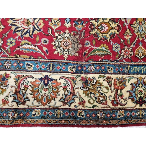 958 - A Red ground Persian Tabriz Carpet with a hand woven and a unique all over floral design nd surround... 